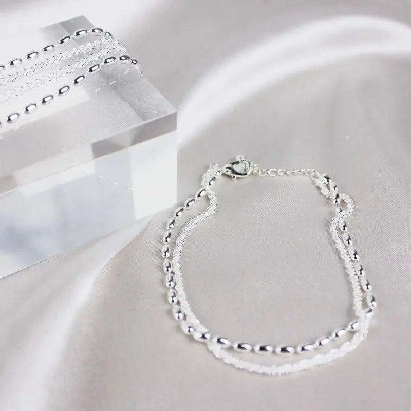 Elegantes Set aus silbernen Armbändern mit Zirkonsteinen